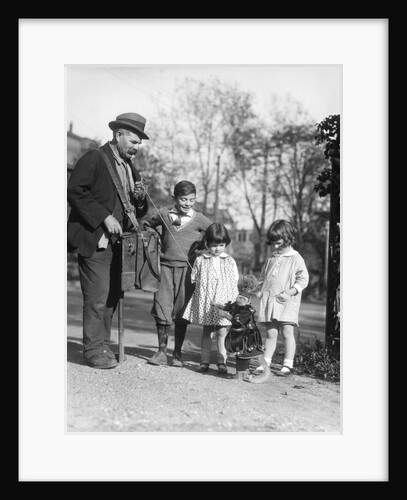 1920s group of three children watching organ grinder's monkey in costume standing on hind legs by Anonymous