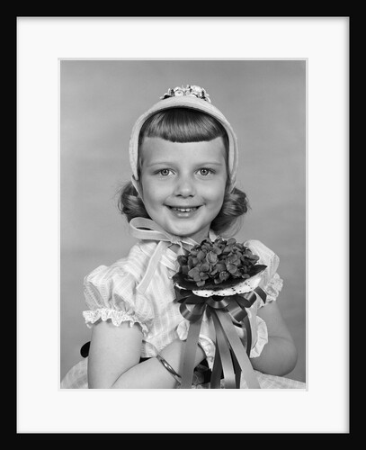 1950s child holding flowers smiling looking at camera by Anonymous
