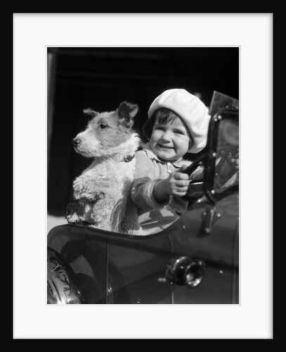 1920s 1930s little girl sitting in toy car steering with dog by Anonymous