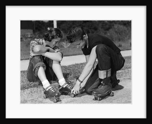 1950s teen boy helping girl put on metal roller skates sitting on sidewalk by Anonymous
