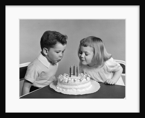 1940s 1950s two children blowing out birthday candles by Anonymous
