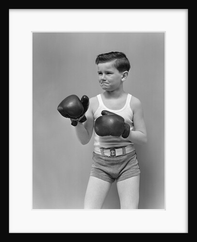 1940s boy child wearing boxing gloves standing ready to fight by Anonymous