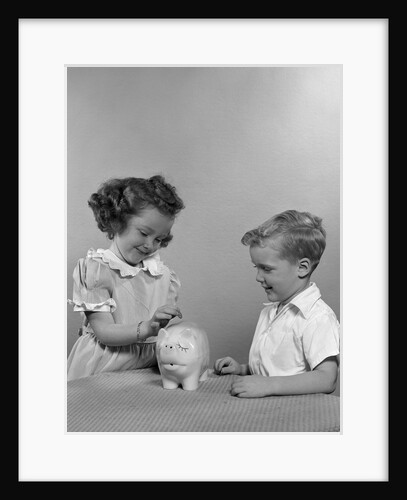 1950s little girl and boy putting coin into piggy bank by Anonymous