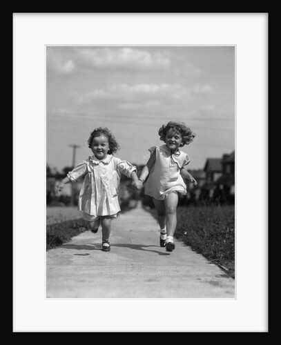 1930s two children running skipping on sidewalk smiling by Anonymous