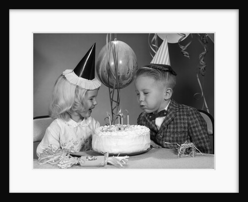 1960s boy blowing out candles on birthday cake by Anonymous