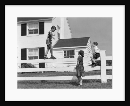 1950s boy walking balancing on fence other children standing sitting next to fence by Anonymous
