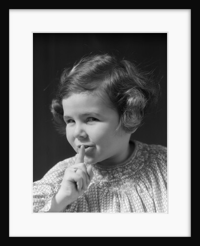1930s little girl with finger to lips making quiet gesture looking at camera by Anonymous