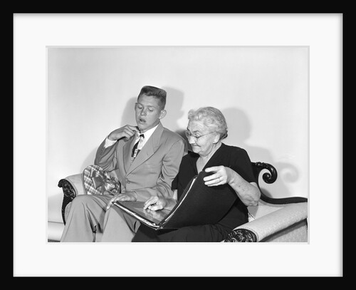 1950s teen boy crew cut suit tie candy box valentine sit next to old woman look photo album first date embarrassment by Anonymous