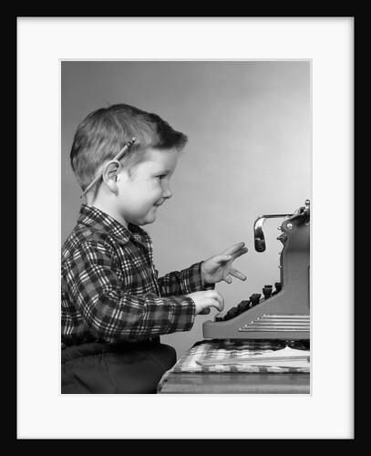 1950s smiling young boy typing on typewriter by Anonymous