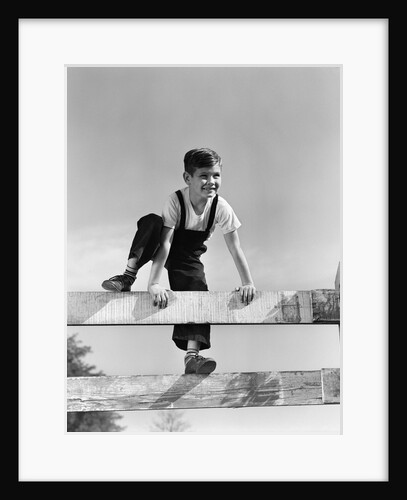 1940s brunette boy wearing overalls climbing over fence by Anonymous