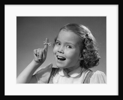 1950s little girl string tied on finger as reminder not to forget smiling looking at camera by Anonymous