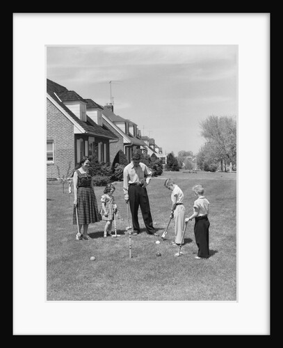 1950s family mother father 3 children playing croquet front lawn suburban home by Anonymous