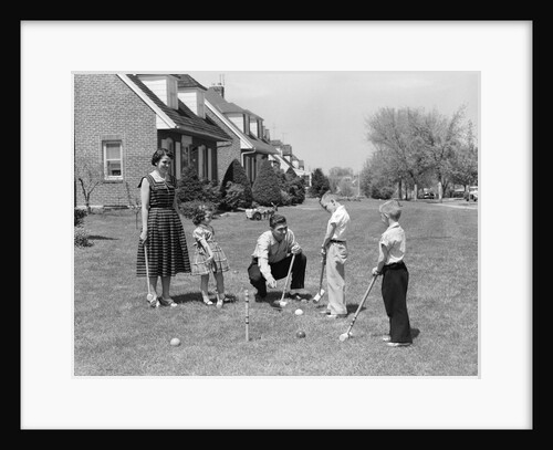 1950s family mother father 3 children playing croquet front lawn suburban home by Anonymous