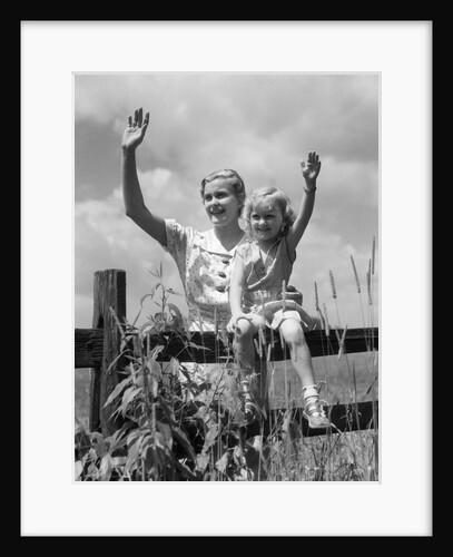 1930s girl sitting on fence with woman next to her in field waving by Anonymous