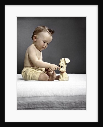 1940s 1950s baby sitting touching toy dog by Anonymous