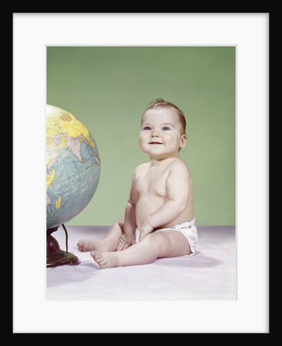 1960s smiling baby wearing diaper sitting beside earth globe by Anonymous