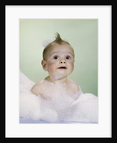 1960s baby sitting in bath surrounded by suds by Anonymous