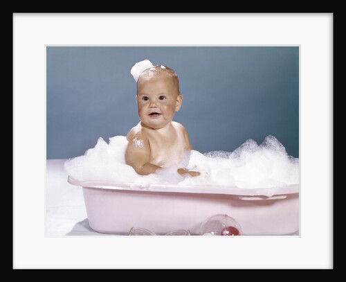 1960s smiling baby sitting in bathtub bubble bath covered with soap bubbles by Anonymous