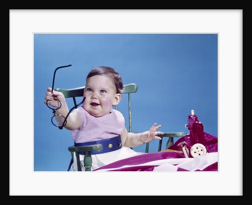 1960s smiling baby holding eyeglasses by Anonymous