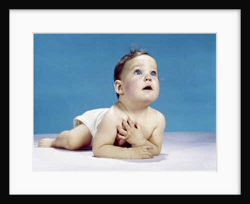 1960s baby lying on stomach looking up hand to chest with sincere facial expression by Anonymous