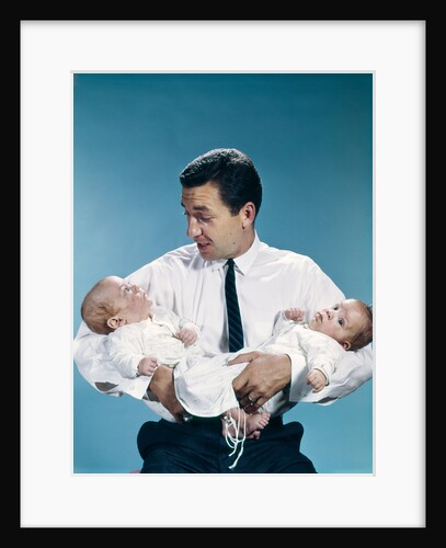 1960s father holding twin babies infants looking down at one of them by Anonymous
