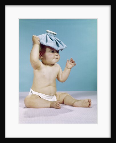 1960s baby sitting with ice pack on top of head by Anonymous