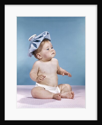 1960s baby sitting with ice pack on top of head by Anonymous