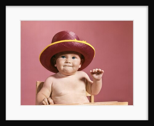 1960s baby making face wearing red straw hat by Anonymous