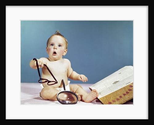 1960s baby holding eyeglasses with open dictionary and magnifying glass research by Anonymous