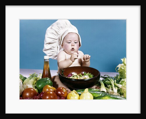 1960s baby making salad wearing chef hat with variety of fresh ingredients vegetables by Anonymous