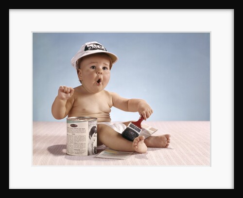 1960s baby with funny facial expression wearing painters cap holding paintbrush sitting by paint can by Anonymous