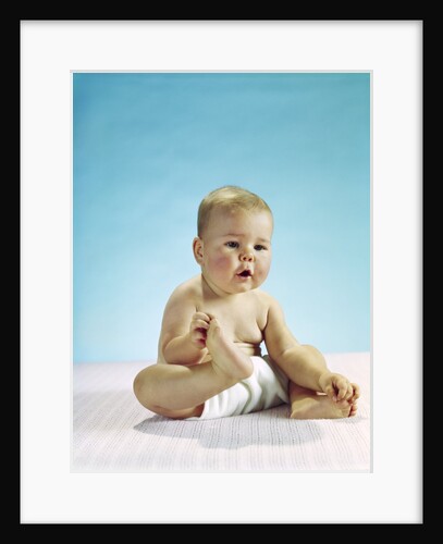 1960s baby sitting holding on to his feet by Anonymous
