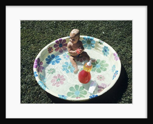 1970s baby sitting in plastic backyard kiddy pool viewed from above by Anonymous