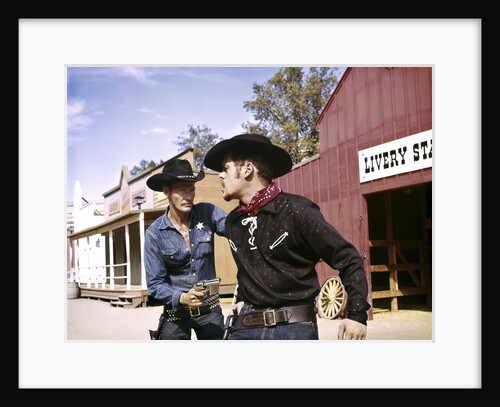 1960s cowboy sheriff with badge draws gun arrests gunfighter in front of livery stable by Anonymous