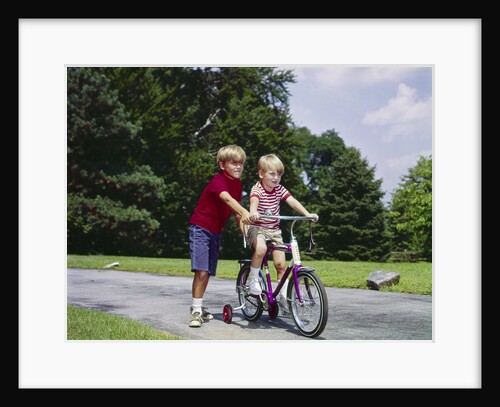 1960s 1970s boy helping little brother ride two wheel bicycle with training wheels by Anonymous