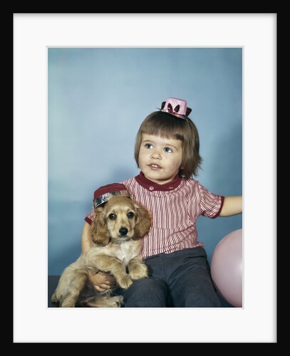 1950s 1960s little girl in party hat sitting holding a cocker spaniel puppy by Anonymous