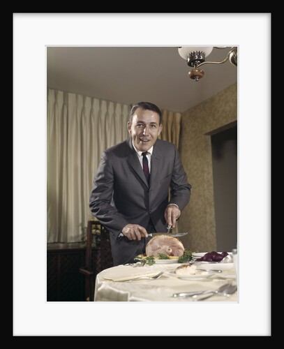 1960s man carving ham dinner looking at camera by Anonymous