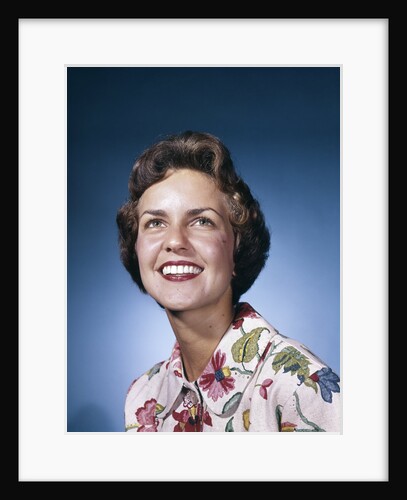 1960s smiling woman in white print dress looking up studio by Anonymous