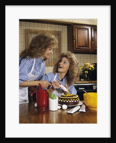 1970s mother daughter dressed alike decorating cake by Anonymous
