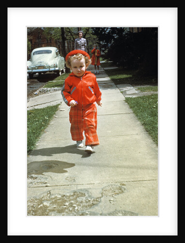 1950s little boy in red outfit running on pavement with mother just behind by Anonymous