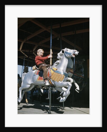 1950s excited boy riding carved wooden carousel merry-go-round horse by Anonymous