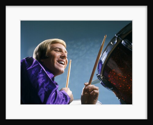 1970s laughing blond man musician playing drums wearing purple shirt by Anonymous