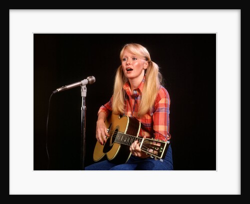 1970s blond young woman ponytails plaid shirt jeans play guitar singing microphone folk singer singers by Anonymous