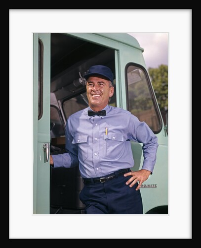 1950s 1960s smiling delivery man wearing uniform work clothes hat bow tie standing in door of step van truck by Anonymous