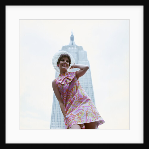 1960s young woman print miniskirt dress summer hat in front empire state building new york city by Anonymous