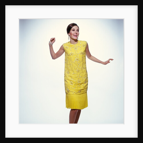 1960s smiling brunette woman modeling yellow sequined cocktail dress clothes by Anonymous