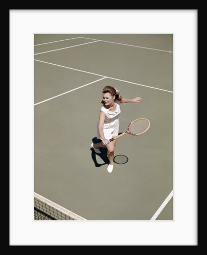 1960s smiling woman playing tennis swinging wood racket to hit ball by Anonymous