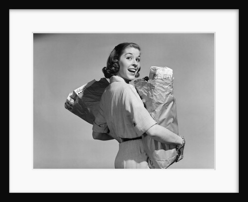 1950s smiling woman carrying grocery bags both hands looking at camera over her shoulder by Anonymous