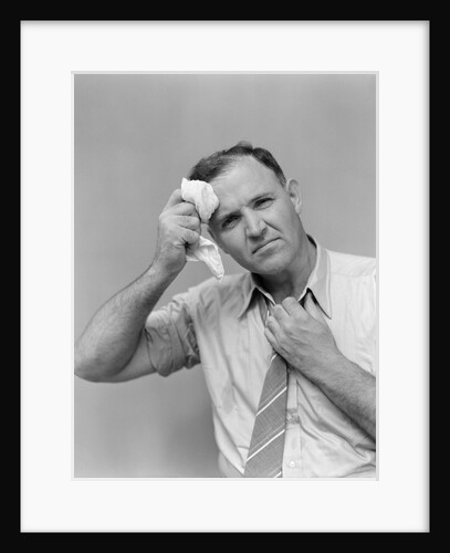 1940s 1950s perspiring man in rolled up shirt sleeves loosening tie holding handkerchief wiping forehead looking at camera by Anonymous