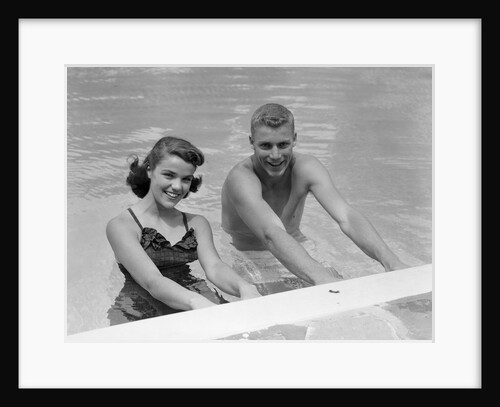 1950s teen couple in swimming pool smiling looking at camera by Anonymous